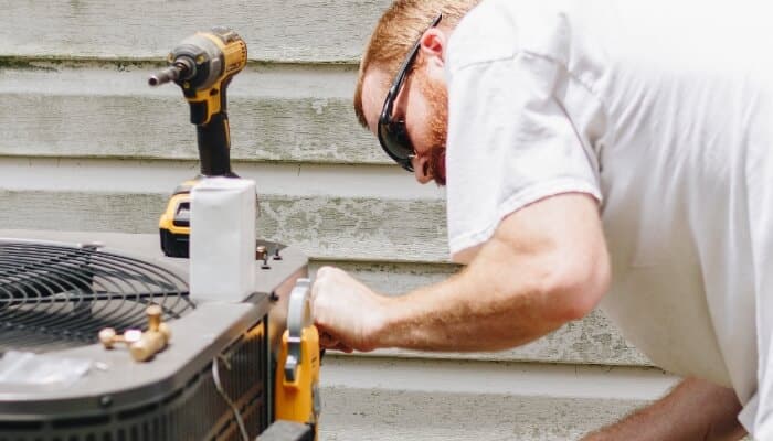 hvac technician performing maintenance on condensor